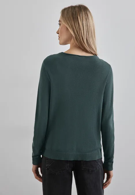 Frau mit grünem Pullover und dunkler Hose, von hinten zu sehen.